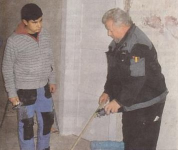 Jürgen Klaas erklärt Sedat Kurt, wie eine Steckdose montiert wird.